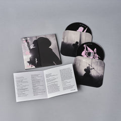 Music album packaging featuring silhouette artwork and lyric booklet.