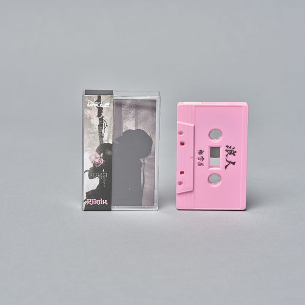 Pink audio cassette tape next to its clear plastic case.