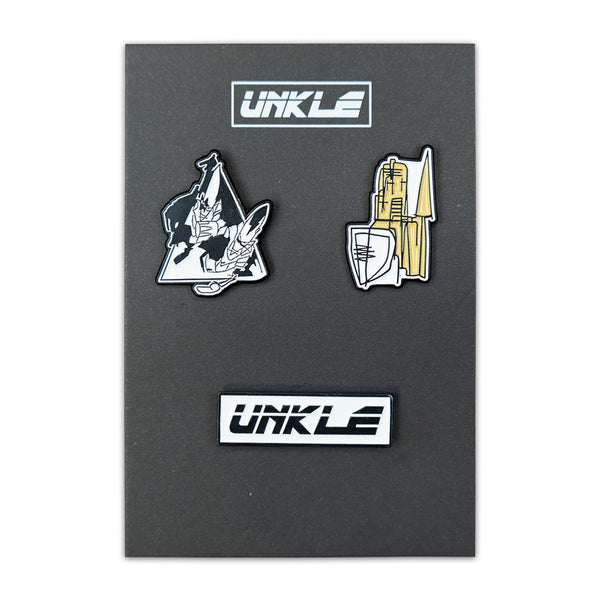 Set of three enamel pins featuring the UNKLE logo and abstract designs on a dark background.